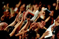 worshippers holding up their hands and Bibles 